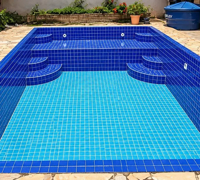 Piscina de alvenaria reformada com pastilha azul nova, degraus e borda de pedra, no Bairro do Portão, em Atibaia