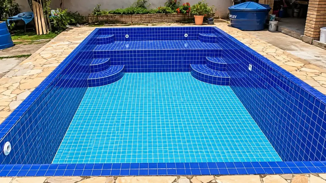 Piscina de alvenaria reformada com pastilha azul nova, degraus e borda de pedra, no Bairro do Portão, em Atibaia