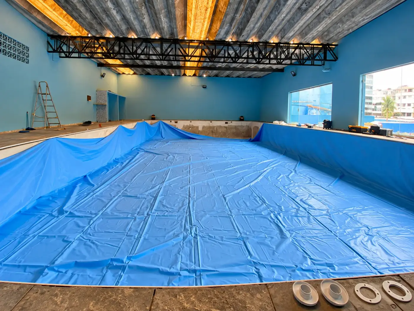 Piscina coberta de academia durante a troca de vinil, com o vinil azul novo sendo instalado