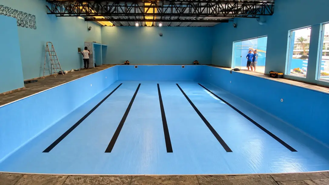 Piscina semi-olímpica coberta de academia com vinil azul novo e raias pretas pintadas no fundo, em São Bernardo do Campo