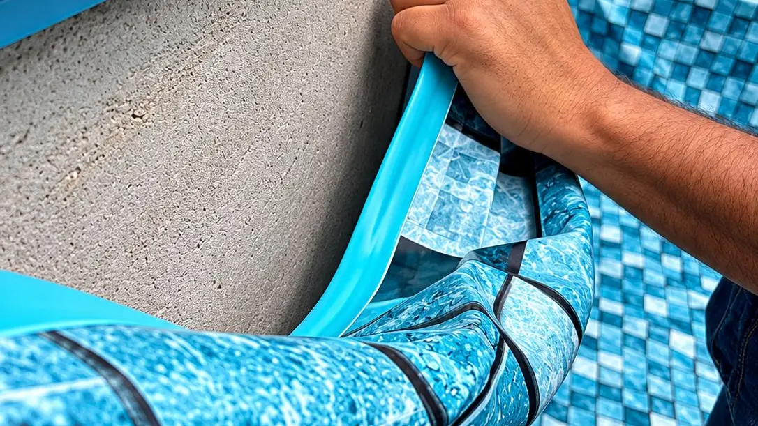 Instalador da Marks encaixando um vinil com estampa de pastilha azul no perfil da borda da piscina