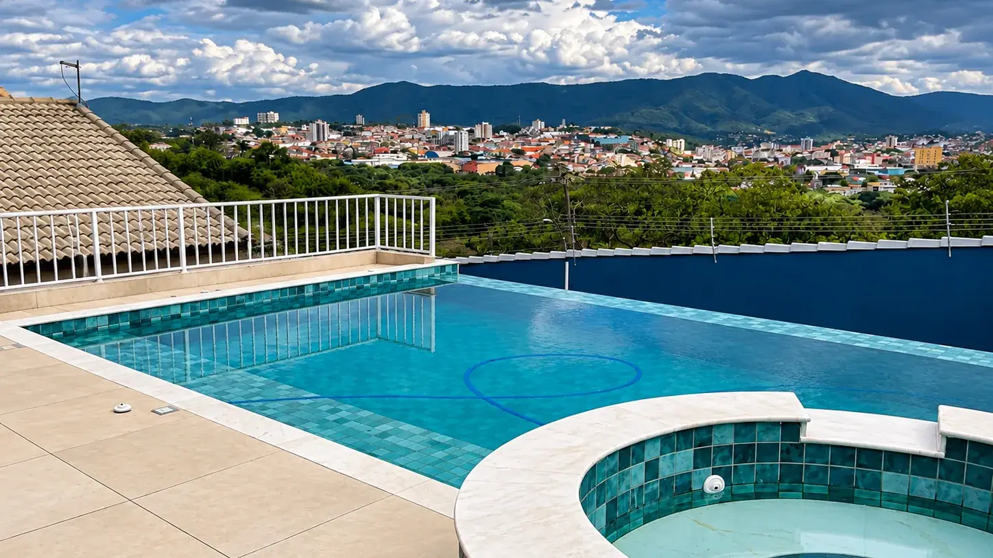 Piscina de alvenaria com revestimento cerâmico verde e spa integrado, com vista para a serra