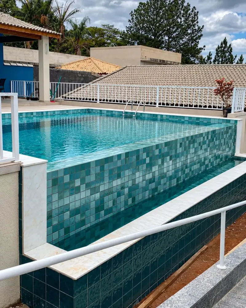 Piscina de alvenaria elevada com pastilha em tons de verde e azul, no São Felipe, em Atibaia