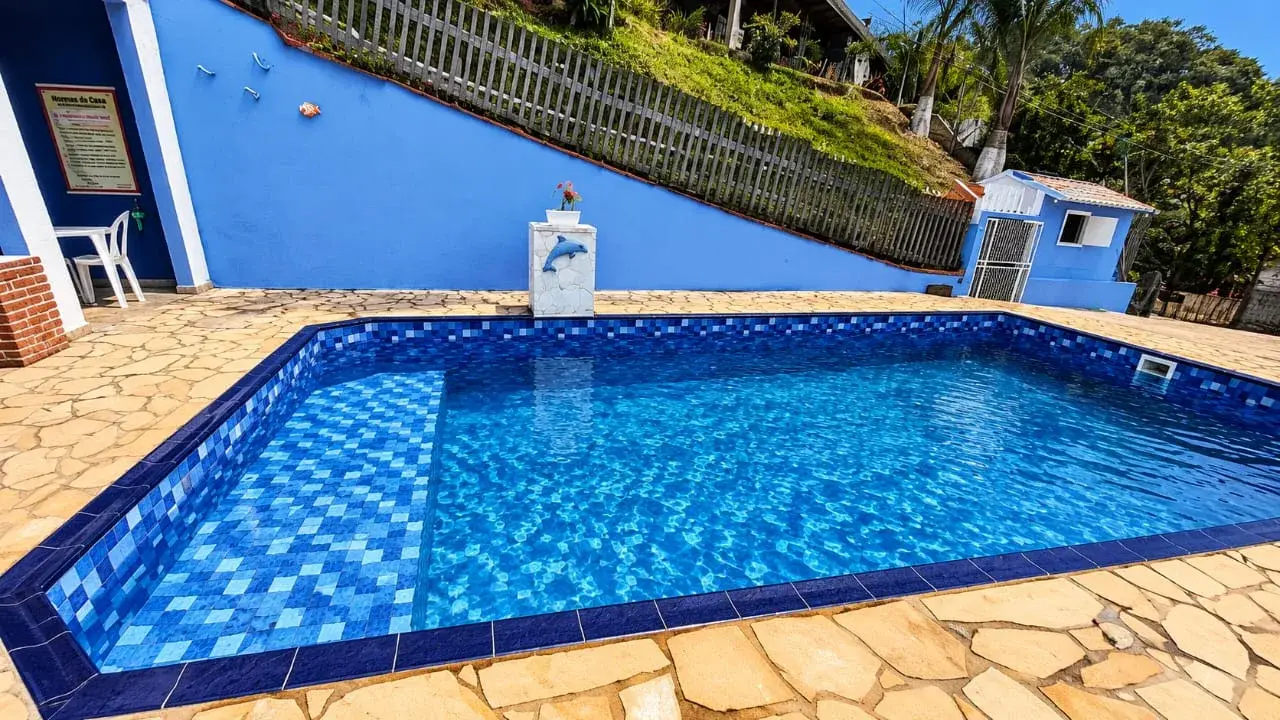 Piscina de vinil retangular com estampa de pastilha azul e deck de pedra, em obra da Marks Piscinas