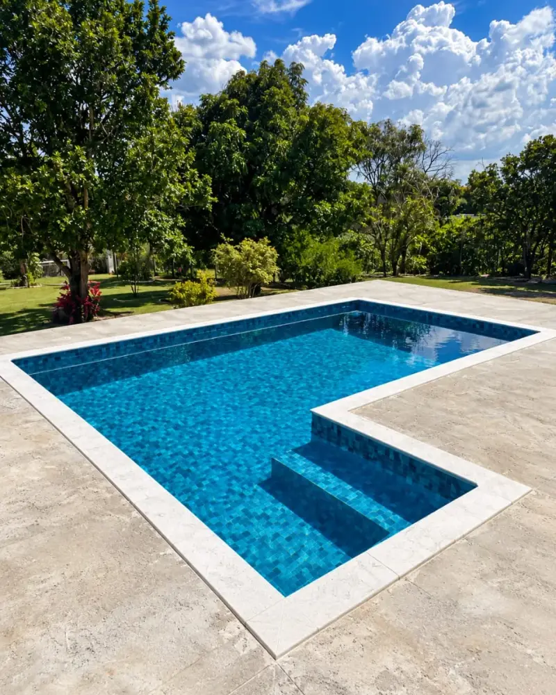 Piscina de vinil compacta em formato de L, com degraus e borda de pedra clara, em Salto de Pirapora