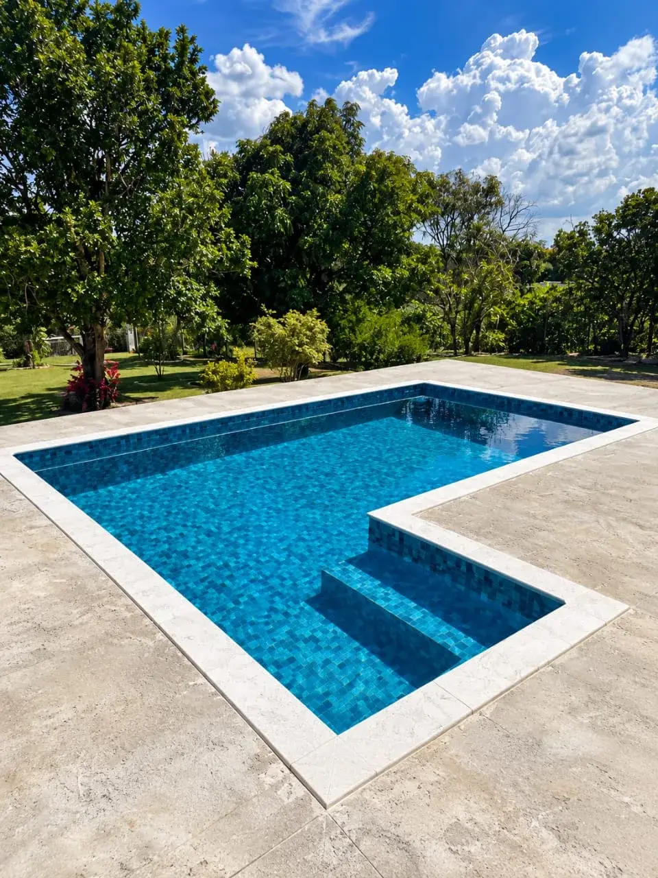 Piscina de vinil compacta em formato de L, com degraus e borda de pedra clara, em Salto de Pirapora